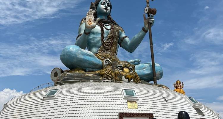 Une grande statue de Shiva sur un dôme entourée de cieux clairs.