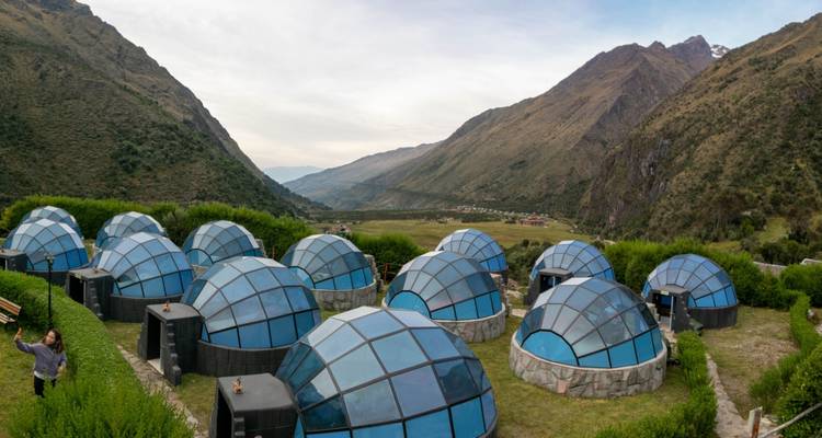 Un conjunto de cúpulas transparentes esparcidas en una terraza verde con vista al valle de Salkantay.