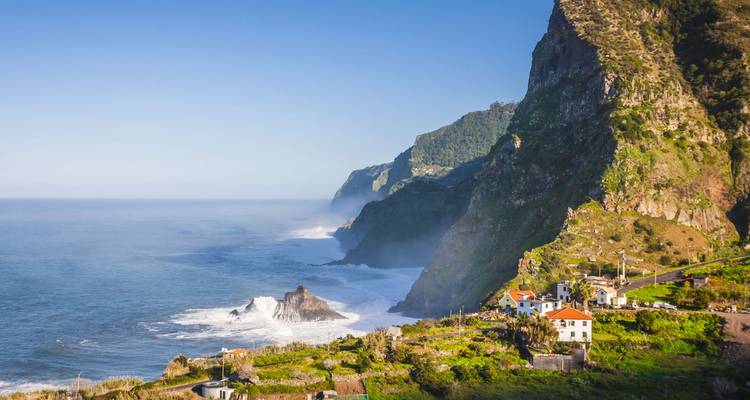 Dramática vista del acantilado costero con olas del océano y casas junto al mar.