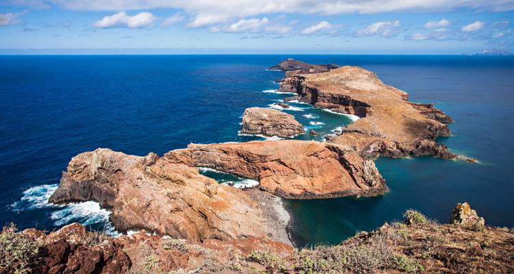 Larga extensión de acantilados rocosos sobre un mar azul profundo bajo cielos despejados.