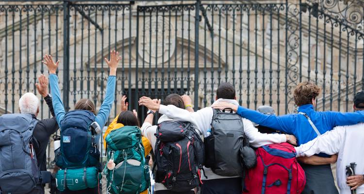 Grupo de personas con mochilas celebrando frente a las puertas