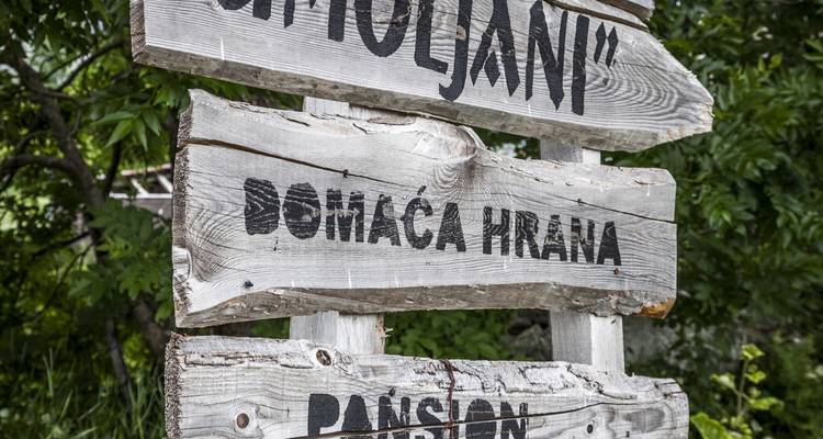 Holzschild mit Text, der auf Botic und Unterkünfte hinweist.