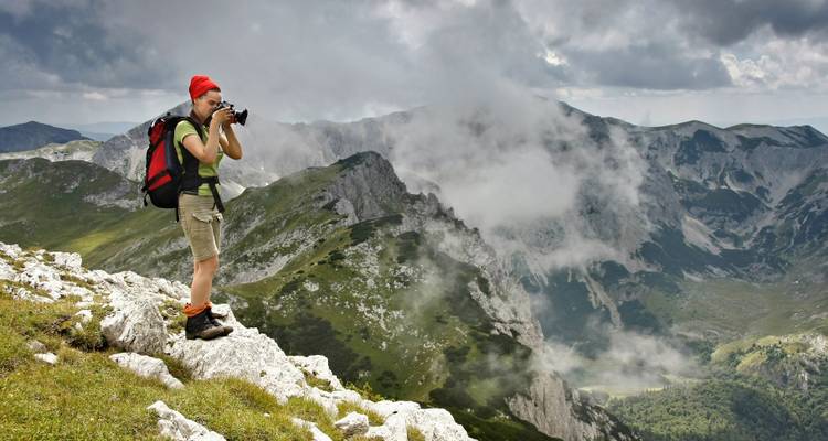 Ein Fotograf hält die neblige Berglandschaft fest.