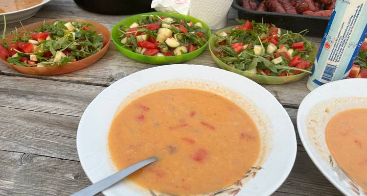 Rustikales Außentischset mit Schüsseln aus hausgemachter Suppe und frischem Salat.