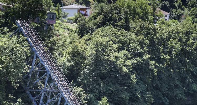 Seilbahn, die durch einen bewaldeten Hügel hinabfährt.