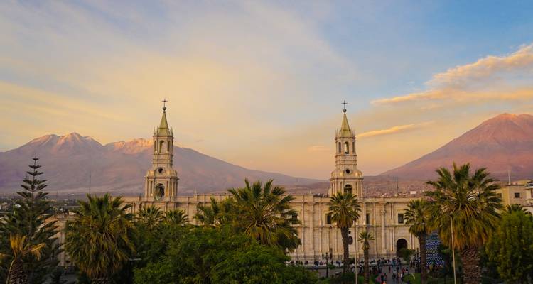 Vista de una catedral con montañas al fondo durante el atardecer.