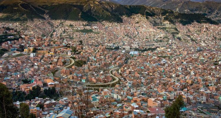 Luftaufnahme einer großen Stadt mit dichter Bebauung und umgebenden Hügeln.