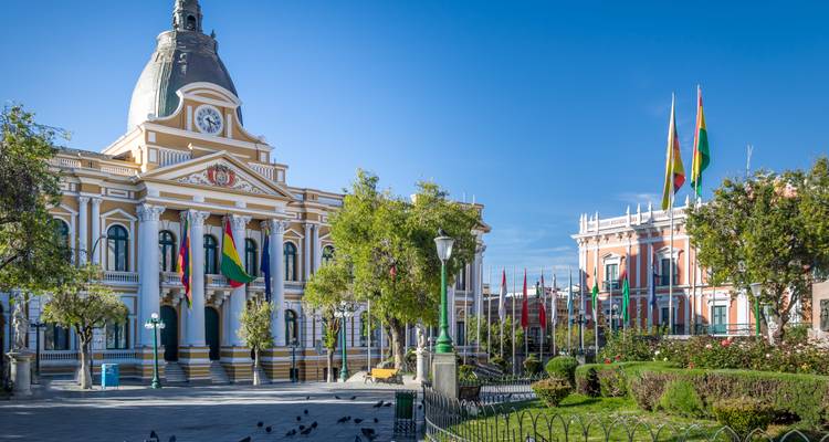 Ein Regierungsgebäude mit Flaggen und einem Uhrenturm unter klarem Himmel.