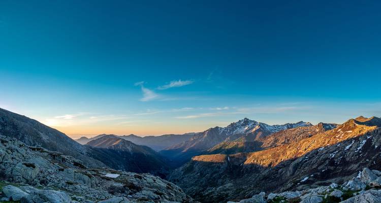 Valle montañoso panorámico al amanecer con picos cubiertos de nieve y tonos cálidos del amanecer sobre Córcega