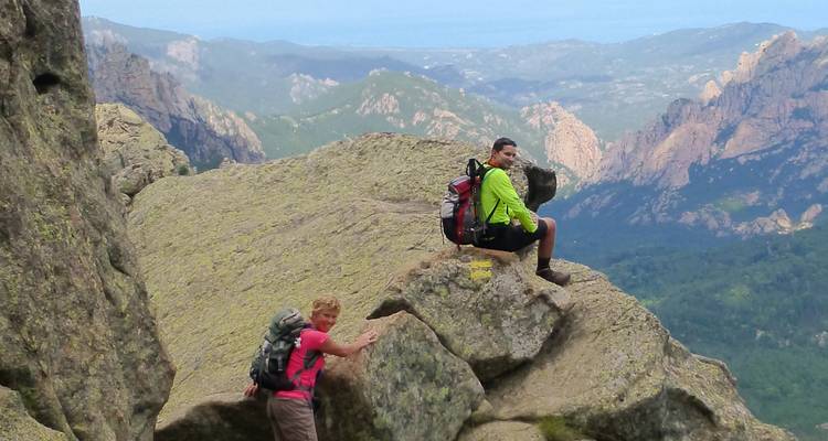 Dos excursionistas sentados en un terreno rocoso con vistas a las montañas.