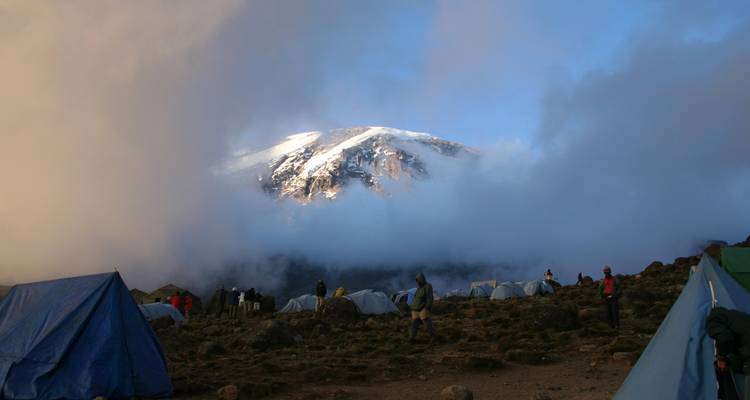 Camp mit schneebedecktem Berggipfel, der teilweise von Wolken bedeckt ist.