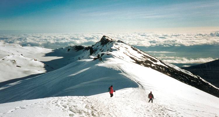 Zwei Menschen, die im Schnee spazieren gehen, mit Blick auf ausgedehnte Wolken.