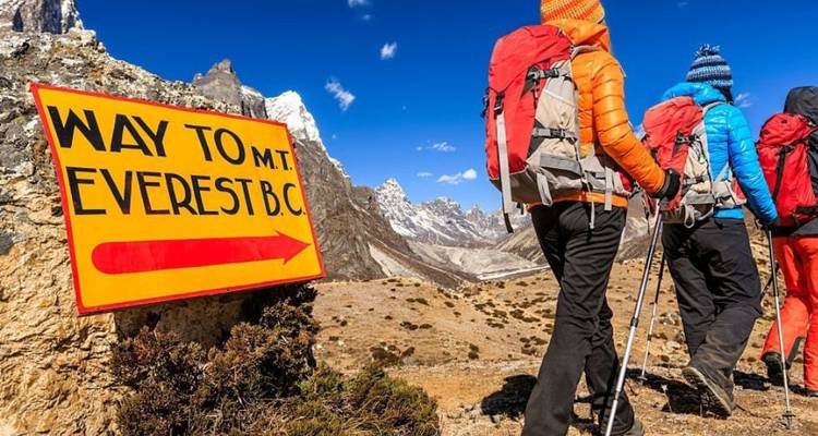 Randonneurs près d'un panneau de col de montagne avec des drapeaux colorés.