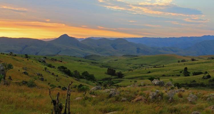 Una vista de colinas onduladas durante la puesta de sol con un cielo colorido.