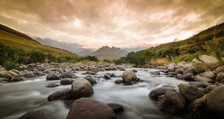 Un río que fluye por un valle con nubes espectaculares.