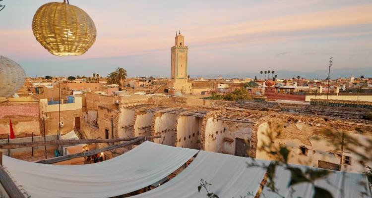 Horizon de Marrakech au coucher du soleil avec une haute tour de minaret.