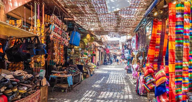 Rue de marché colorée avec textiles et décorations à Marrakech.