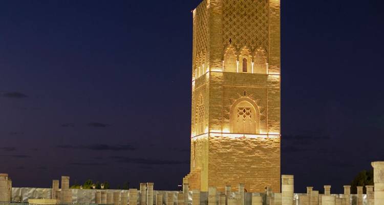 Tour de Rabat illuminée la nuit avec les ruines environnantes.