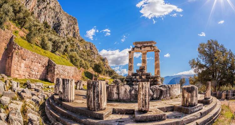 Ruines antiques entourées de montagnes et de soleil.