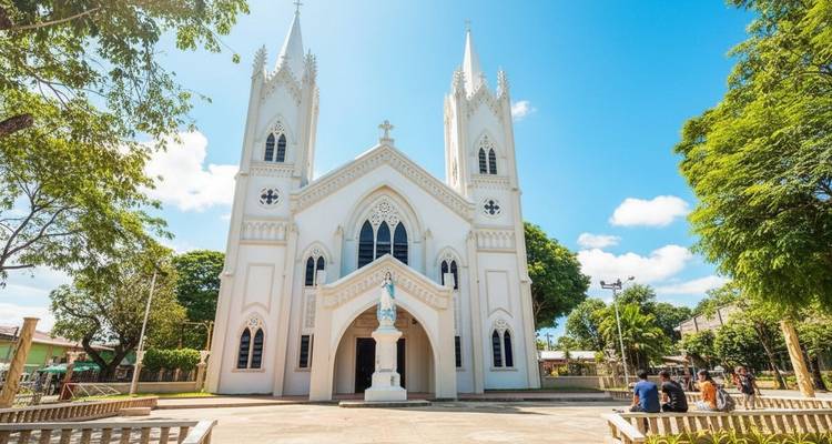 Cathédrale blanche avec des flèches et une statue devant, sous un ciel bleu.