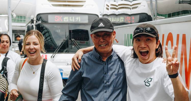 Viajeros sonrientes saludando a un conductor de autobús amistoso afuera de un autocar en una terminal