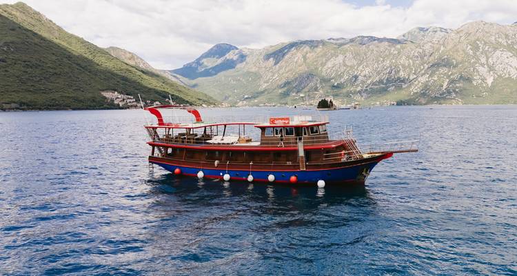 Scenic view of a boat in the water with mountainous backdrop.