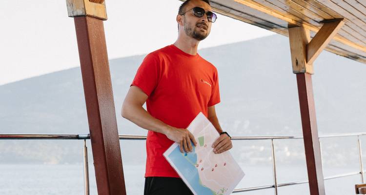 Person in a red shirt holding a map on a boat.