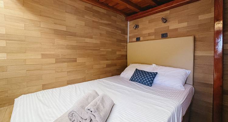 Interior view of a cozy cabin room with a bed and towels.