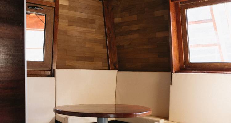 Interior of a wooden cabin with windows and a round table.