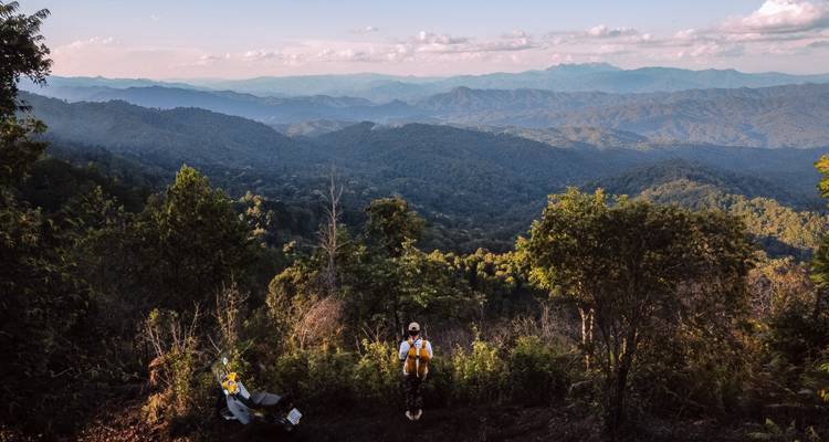 Personne debout sur un point de vue montagneux avec des vues étendues sur la forêt.