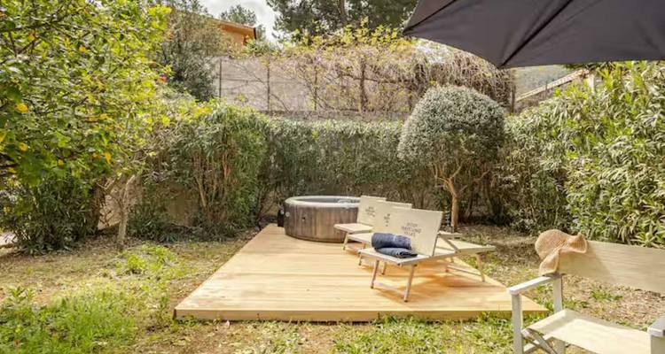 Jardin avec des chaises et un parasol.