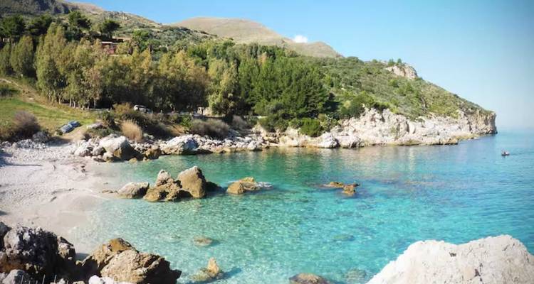 Vue panoramique d'une plage avec une eau claire et des falaises.