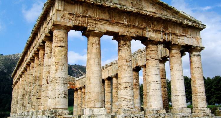 Colonnes antiques d'un temple sous un ciel bleu.