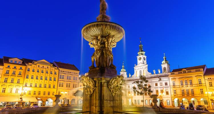 Blauwe-uurtje zicht op het hoofdplein van Ceske Budejovice met verlichte barokke fontein en historische gebouwen.