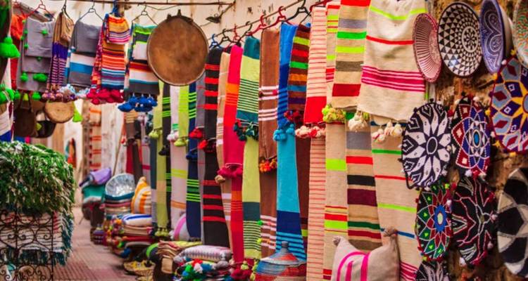 Des textiles colorés exposés dans un marché animé.