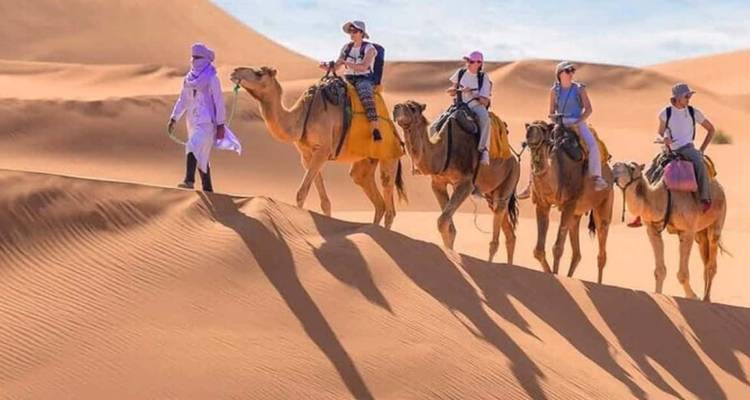 Un groupe chevauchant des chameaux à travers les dunes du désert.