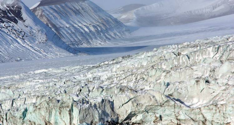 Uitgestrekt uitzicht op gletsjer met besneeuwde bergen.