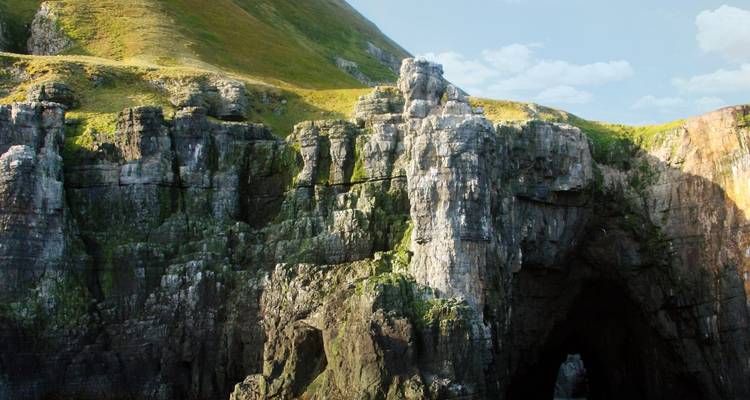 Rotsachtige kliffen met een grot op een zonnige dag.