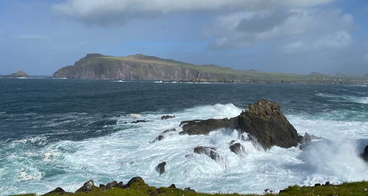 Powerful Atlantic waves crash against rugged rocks beneath green headlands on the Dingle Peninsula