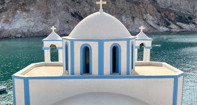 Gros plan d'une église blanche et bleue surplombant la mer.