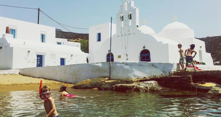 Des enfants jouent dans l'eau près d'une église blanche.
