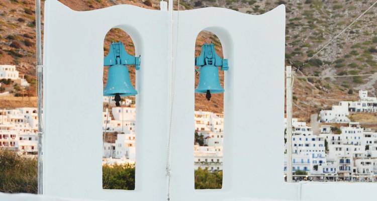 Cloches d'église sur fond de village à flanc de colline.