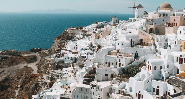 Vue panoramique de bâtiments blancs sur une colline surplombant la mer.