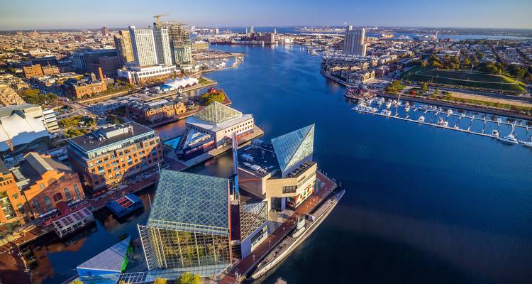 Vista aérea de un paisaje urbano con frente marítimo y edificios modernos bajo un cielo despejado.