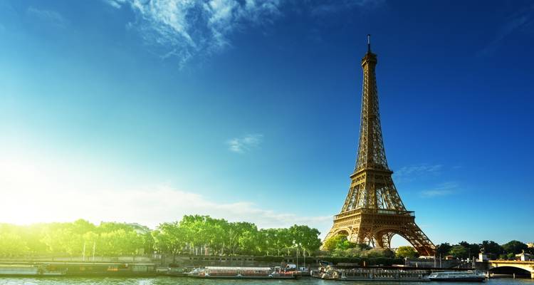 Clear morning view of the Eiffel Tower against a vivid blue sky and the Seine waterfront.