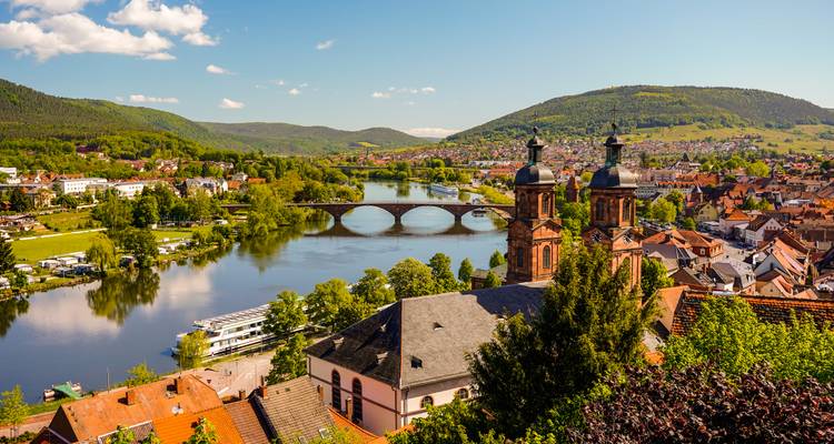 Vista panorámica de una escena del río con colinas e iglesia histórica.