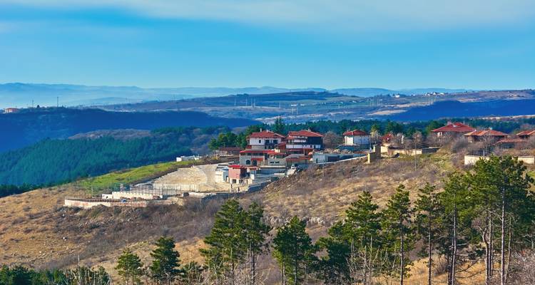 Small hilltop village overlooking rolling forests and distant mountains.