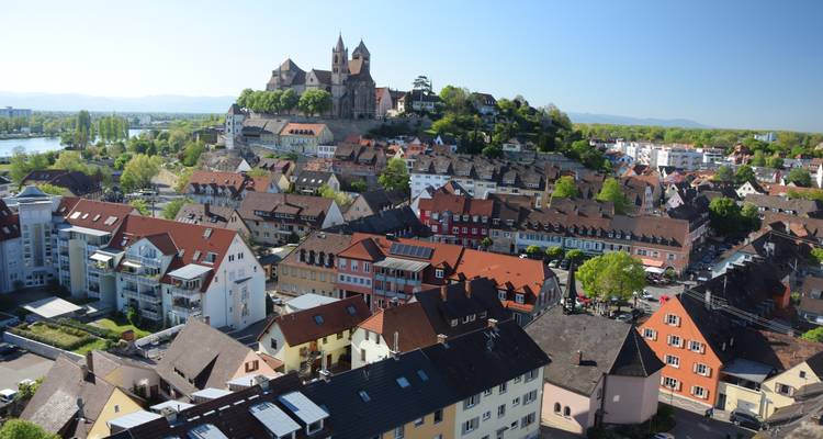Iglesia en la cima de la colina con vista al pueblo compacto de Breisach am Rhein con techos de terracota bajo un cielo azul claro.