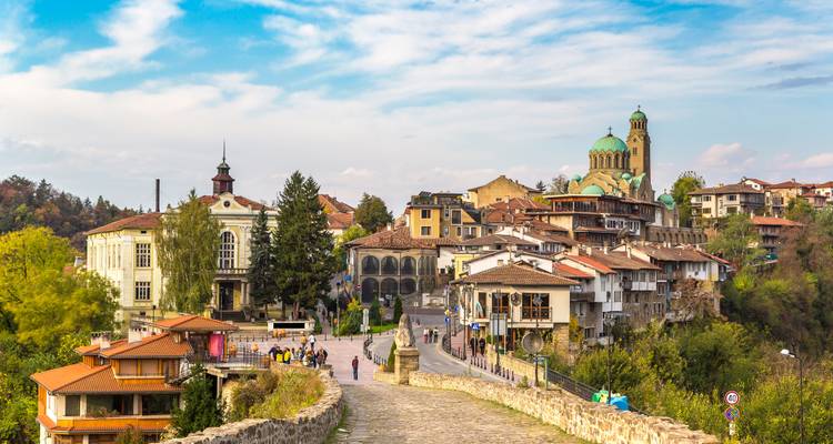 Stone bridge leading into the picturesque hillside town of Veliko Tarnovo with historic churches.