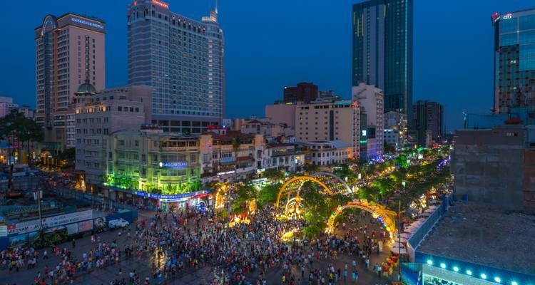 Vista aérea nocturna de la Calle Peatonal Nguyen Hue en la Ciudad de Ho Chi Minh repleta de multitudes celebrando y luces.